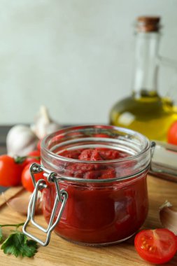 Domates ezmeli kavanoz ahşap masada malzemelerle.