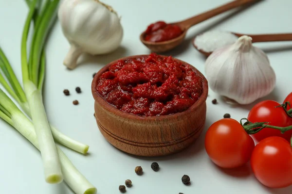 Tahta kasede domates ezmesi ve beyaz arka planda malzemeler var.