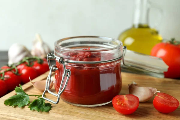 Domates ezmeli kavanoz ahşap masada malzemelerle.