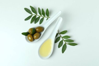 Zeytinli ve yağlı kaşıklar ve beyaz arka planda dallar.