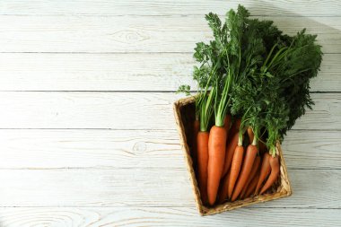 Beyaz ahşap masadaki havuçlu sepet.