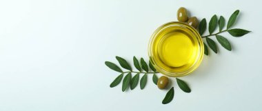 Beyaz arka planda bir kase yağ, zeytin ve dal.