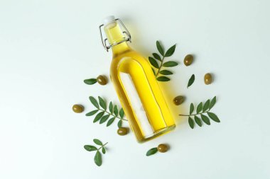 Beyaz arka planda bir şişe yağ, zeytin ve dal.