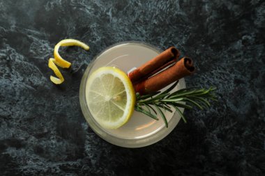Siyah dumanlı masada tarçınlı ve biberiyeli bir bardak limonata.
