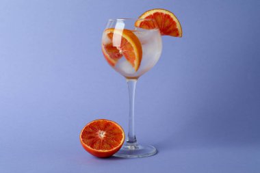 Menekşe arkaplanda greyfurt olan bir bardak kokteyl.