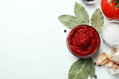 Beyaz zemin üzerinde domates ezmesi ve malzemelerle dolu bir kase.