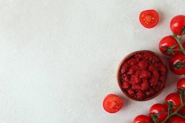 Tahta kase, domates ezmesi ve domatesler beyaz desenli masa.