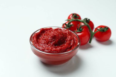 Beyaz arka planda bir kase domates ezmesi ve domates.