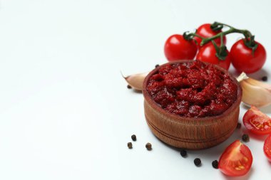 Beyaz arkaplanda bir kase domates, biber ve sarımsak.