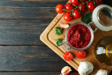 Domates ezmeli kavanoz ahşap masada malzemelerle.