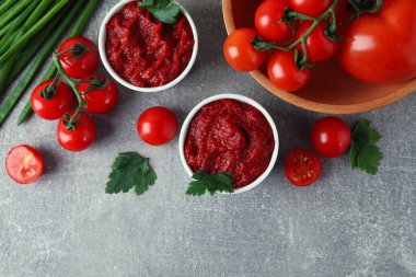 Gri arka planda domates ezmeli kaseler ve malzemeler.