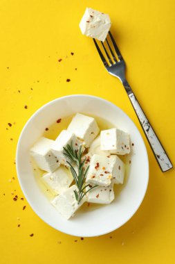 Sarı arka planda peynirli kase ve çatal.