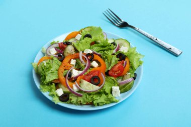 Mavi arka planda Yunan salatası ve çatal tabağı