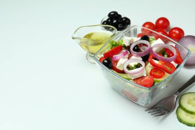 Beyaz arka planda bir kase Yunan salatası ve malzemeleri