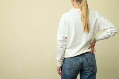 Bej arka planda beyaz kazaklı genç bir kadın.