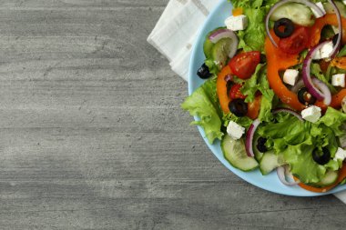 Gri desenli arka planda Yunan salatası ve mutfak havlusu.