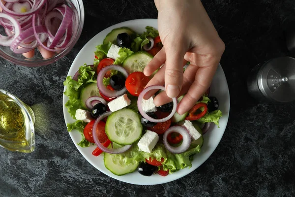 Vrouwelijke Hand Zet Uien Griekse Salade Zwarte Smokey Achtergrond — Stockfoto