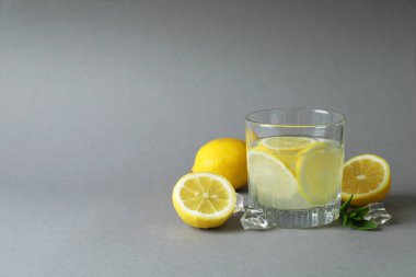 Açık gri arka planda bir bardak limonata ve malzemeler.
