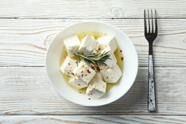 Beyaz ahşap arka planda beyaz peynir ve çatalla kase