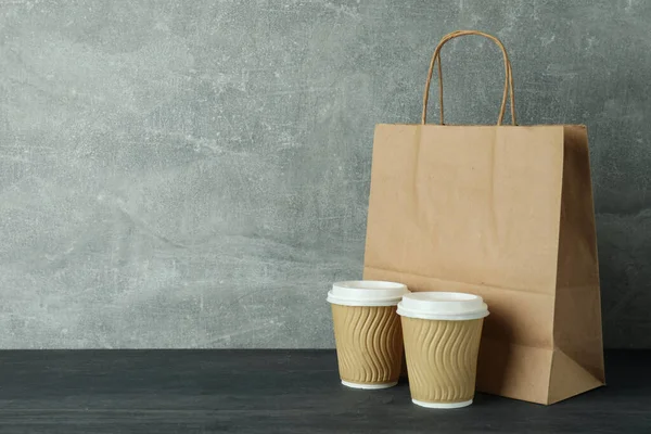 Paper cups and bag on dark wooden table