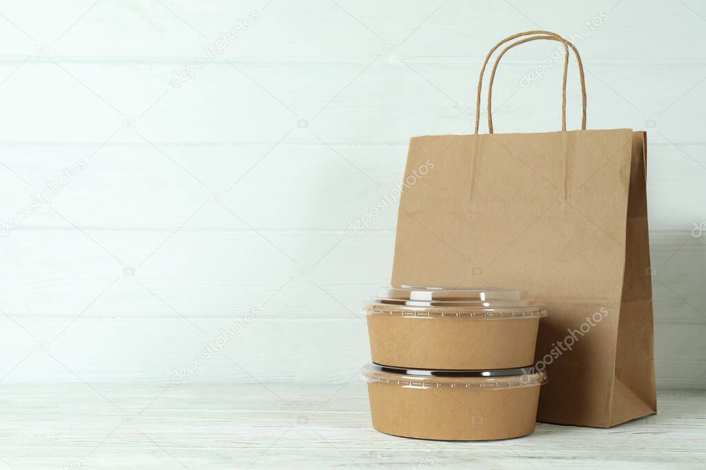 Paper bowls and paper bag on white wooden table
