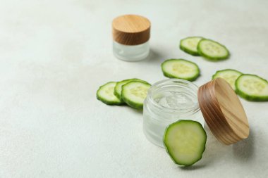 Beyaz desenli arka planda kozmetik ve salatalık dilimleri olan kavanozlar.