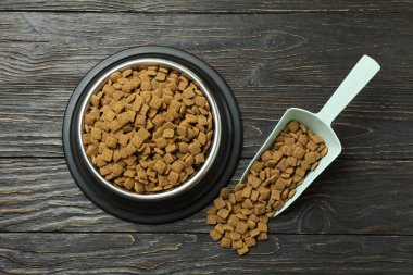 Evcil hayvan kasesi ve kepçeyle ahşap arka planda besleme