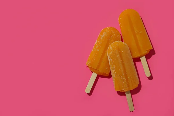Mango or caramel ice cream sticks on pink background