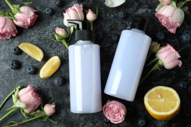 Doğal duş jelleri ve siyah dumanlı arka plandaki malzemeler