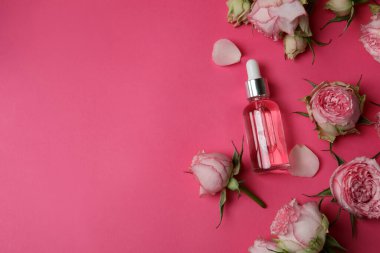 Pembe arka planda gül yağı içeren cilt bakımı kavramı