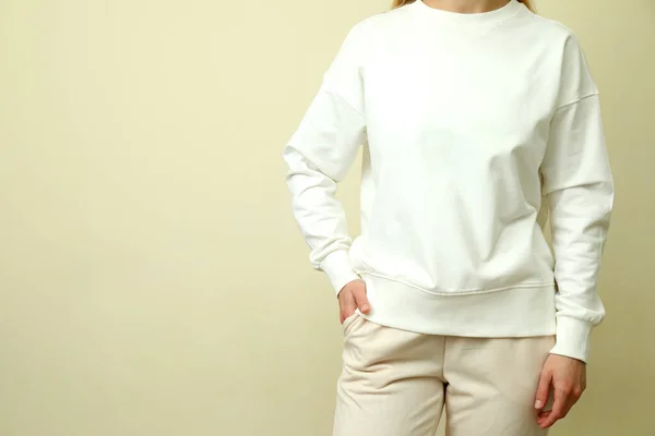 若いです女性で白いスウェットシャツに対するベージュの背景 — ストック写真