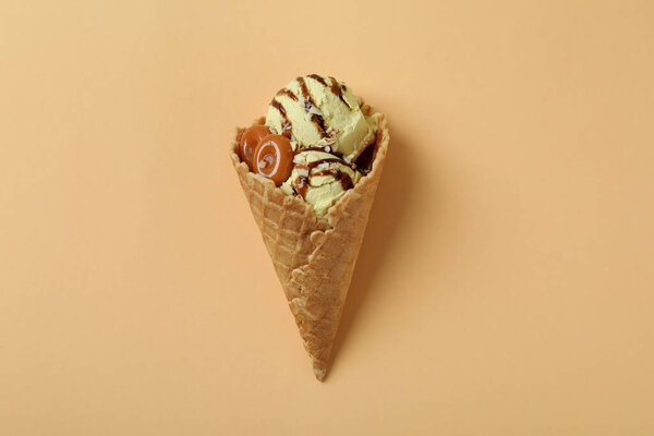 Конус из карамельного мороженого на бежевом фоне