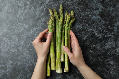 Kadın elleri siyah dumanlı arka planda kuşkonmaz tutar
