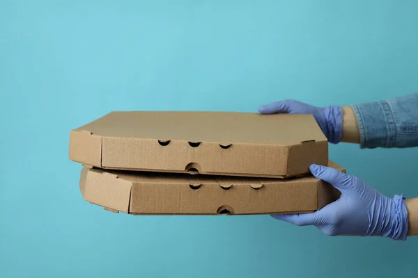Hands in gloves hold pizza boxes on blue background