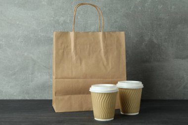 Kağıt bardaklar ve çantalar koyu ahşap masada.