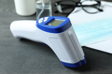 Siyah ahşap arka planda tıbbi aletler ve termometre tabancası.