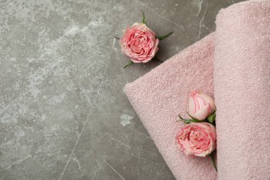 Gri desenli masada pembe katlanmış havlular ve güller.