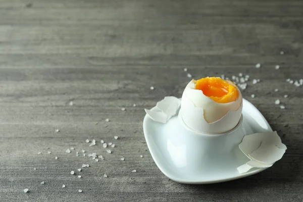 Boiled egg and salt on gray textured background