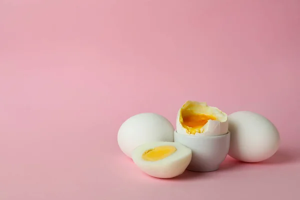 Tasty boiled eggs on pink background, space for text