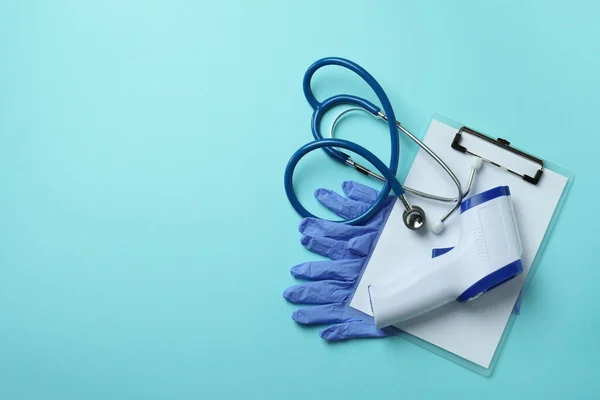 Medical tools and thermometer gun on blue background