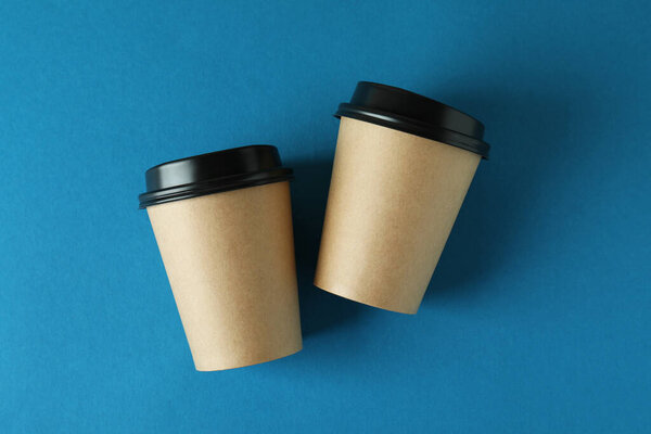 Blank paper cups on blue background, space for text