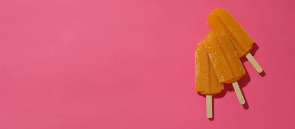 Mango or caramel ice cream sticks on pink background