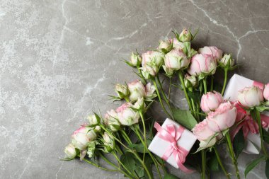 Gri desenli arka planda güller ve hediye kutuları