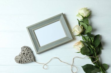 Güller, kalp ve boş çerçeve beyaz ahşap arka planda