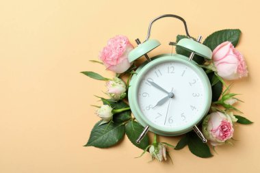 Bej arkaplanda güller ve çalar saat