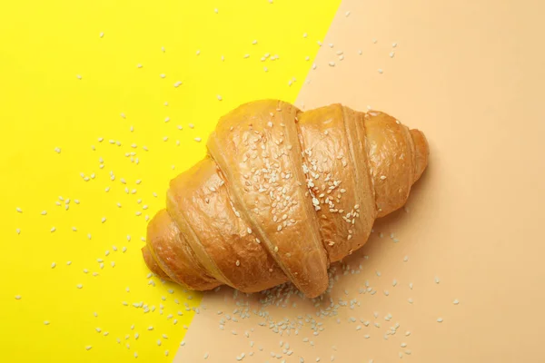 Croissant and sesame on two tone background, top view