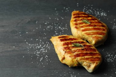 Koyu ahşap arka planda ızgara tavuk eti ve tuz.