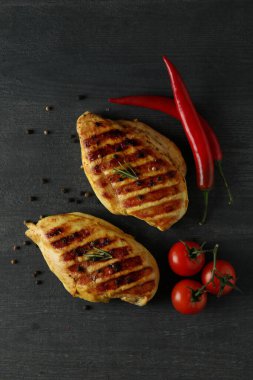 Koyu ahşap arka planda ızgara tavuk eti ve baharat.