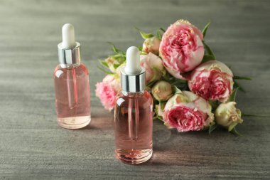 Gri desenli arka planda gül yağı içeren şişeler