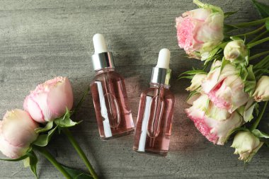 Gri desenli arka planda gül yağı içeren şişeler